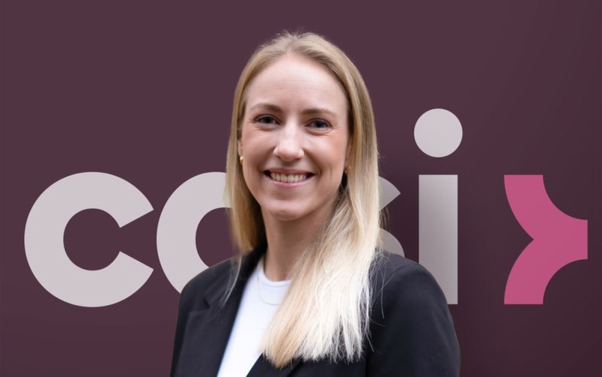 Portrett av Elise fra Casi i svart blazer mot mørkerød bakgrunn med Casi-logoen