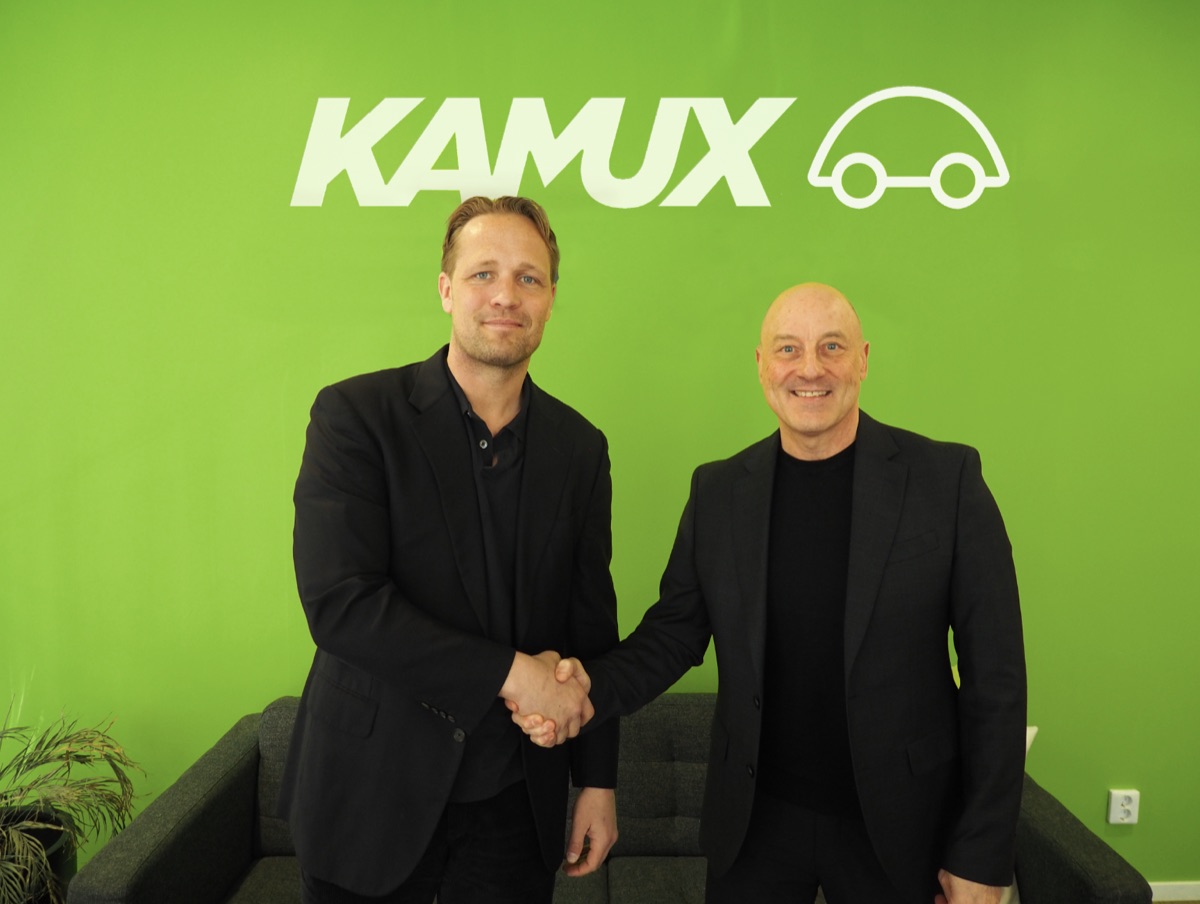 Två män skakar hand framför en ljusgrön Kamux-vägg, Kamux och Gire tecknar partnerskap