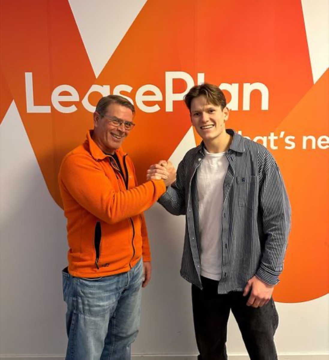 To menn gir hverandre hånden foran en oransje LeasePlan-vegg, LeasePlan og Gire-samarbeid