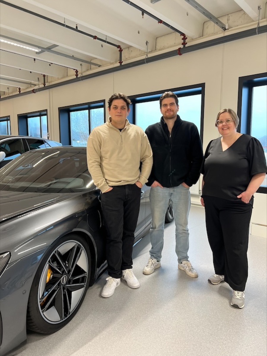 Tre personer ved siden av en mørkegrå Audi på et karosseriverksted, Møller Skadesenter og Gire