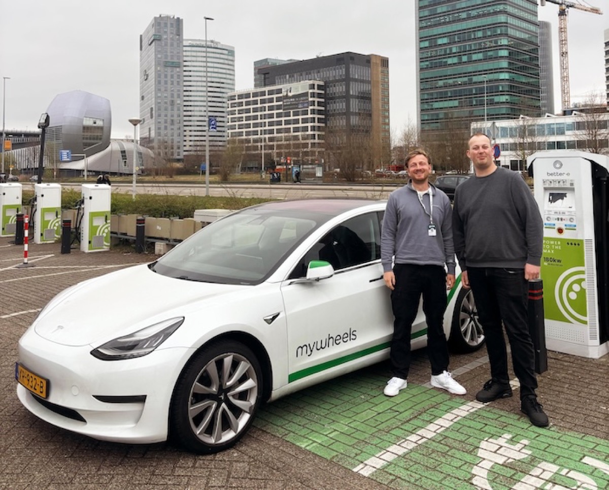Twee mannen naast een MyWheels Tesla Model 3 bij een laadpaal in Amsterdam