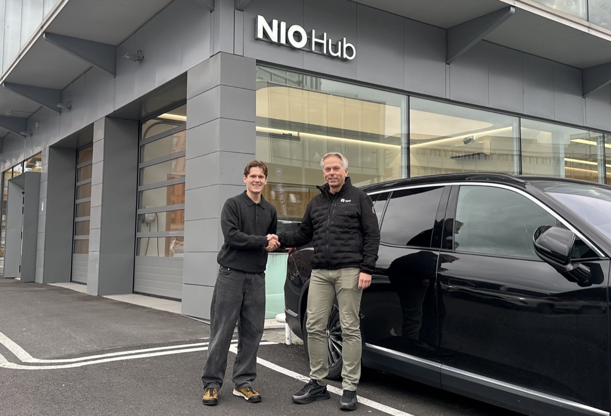 To menn gir hverandre hånden utenfor NIO Hub ved siden av en svart NIO elbil