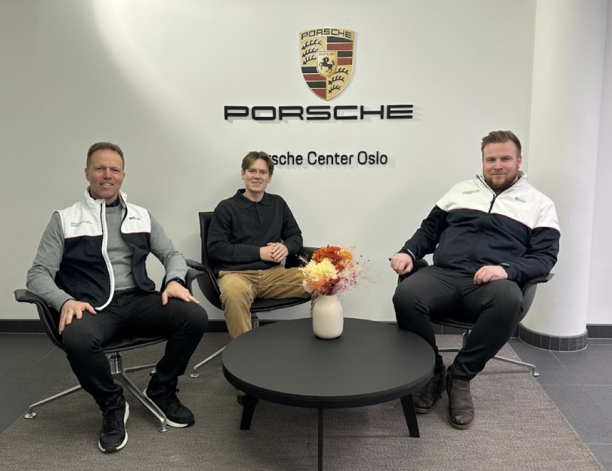 Tre menn sitter i Porsche Center Oslo under Porsche-emblemet, partnerskapsmøte