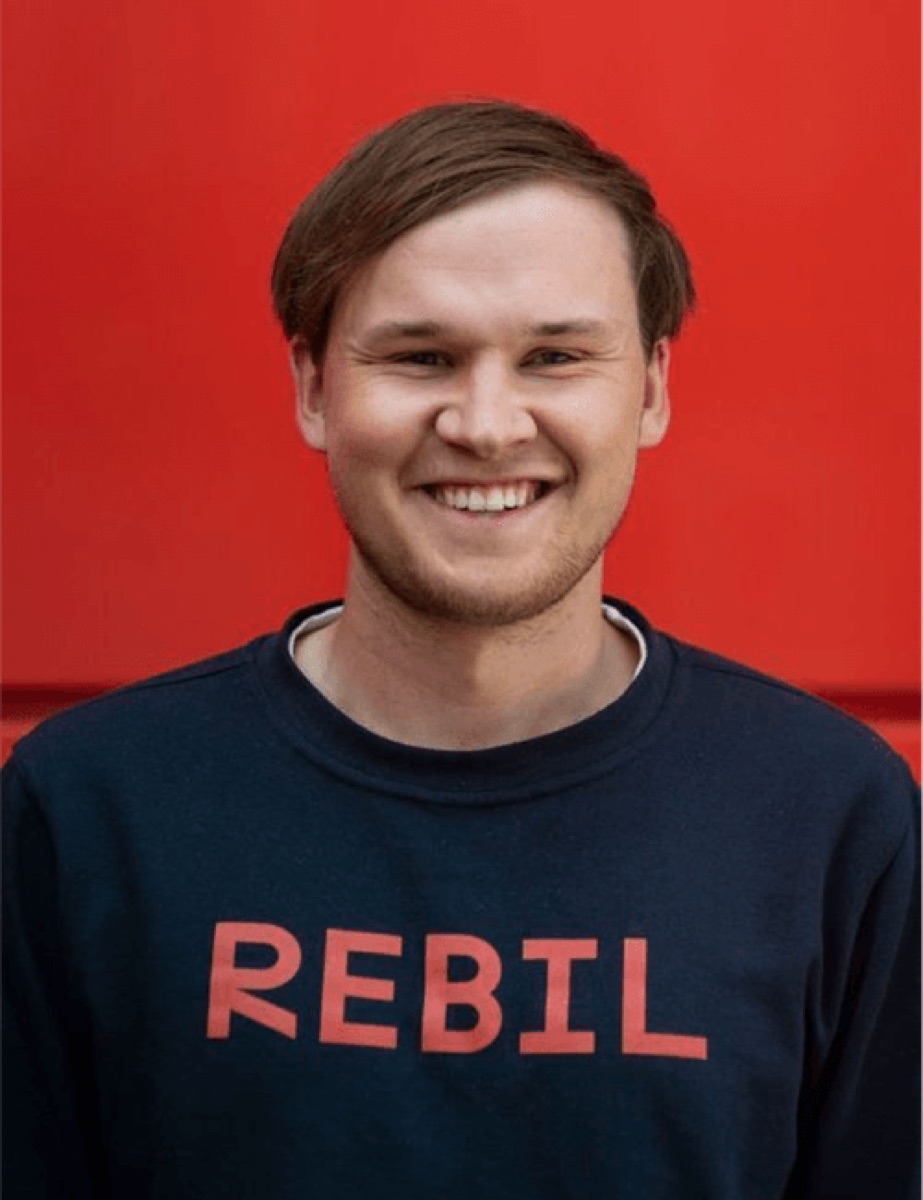 Portrett av Ruben Davidsen fra Rebil i marineblå sweatshirt mot rød bakgrunn
