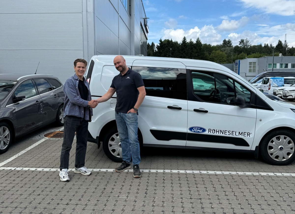 To menn gir hverandre hånden på et næringsområde foran en hvit Ford Røhneselmer-varebil