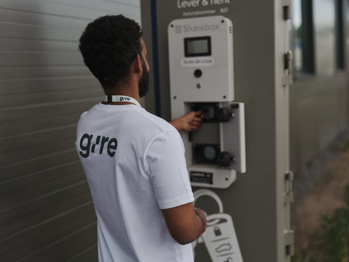 Gire-sjåfør i hvit Gire-t-skjorte som åpner en Sharebox elektronisk nøkkelboks på en vegg