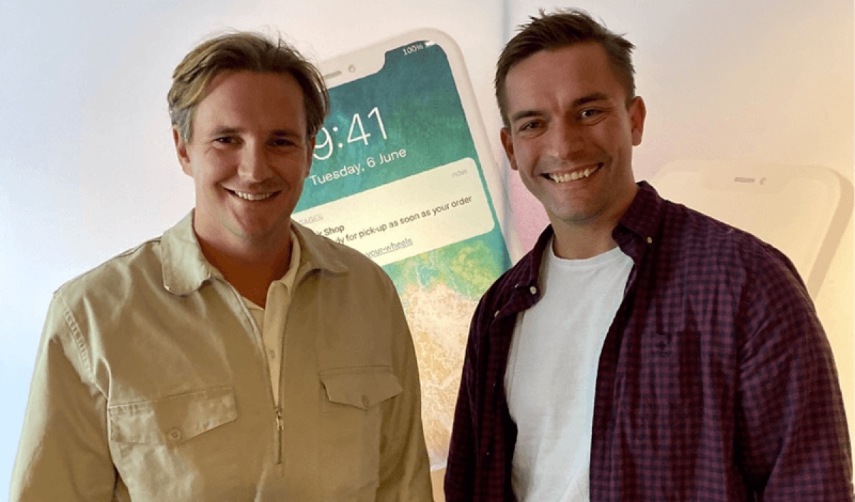 To menn smiler foran en stor smarttelefongrafikk, Gire og Spense-samarbeid